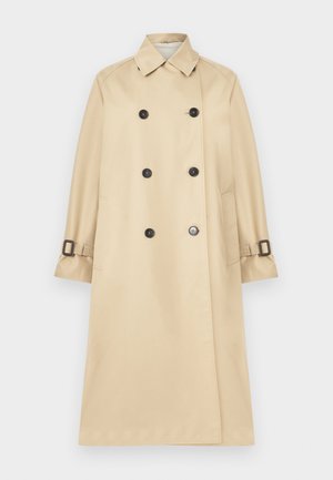 Trench-coat beige croisé avec boutons noirs, col, deux poches latérales et sangles à boucle aux manches.