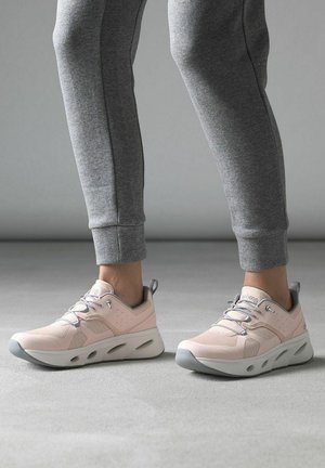 Světle růžové sportovní boty s texturovaným svrškem a šedými akcenty. Zaoblená podrážka s výřezy pro prodyšnost a flexibilní pohyb.
