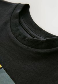 Juodas medvilnės marškinėlis su įpjovimu aplink kaklą, lygiu paviršiumi ir kontrastingu įvairių spalvų grafikiniu dizainu priekyje.