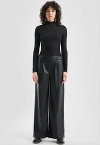 Czarny prążkowany golf w połączeniu z szerokimi czarnymi spodniami z eko skóry, ozdobionymi guzikami na pasku. Gładka faktura, dopasowany krój.