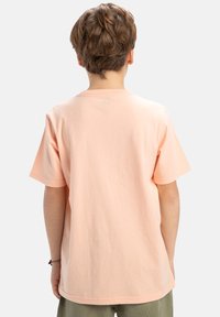 Persikofärgad bomulls-t-shirt med korta ärmar, avslappnad passform och rund halsringning. Slät textur, minimalistisk design utan mönster eller logotyper.