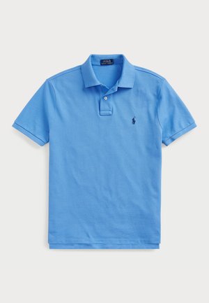 Polo de color azul claro, hecho de algodón suave, con cuello clásico, tapeta de dos botones y un logo bordado en el lado izquierdo del pecho.