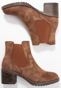 Brown suede ankle boots with elastic side panels, square toe, and a chunky wooden heel; textured finish gives a soft appearance.