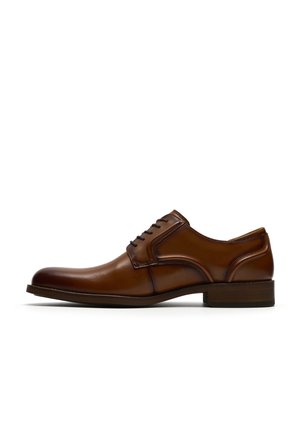 Brauner Herrenschuh aus Leder mit geschlossenem Schnürsystem, niedrigem Absatz und eleganter abgerundeter Spitze, in Seitenansicht auf weißem Hintergrund dargestellt.