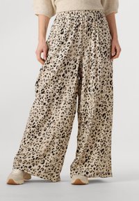 Wide-legged leopard print pants in beige and black, featuring an elastic waistband and flowing fabric with a soft texture.