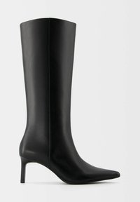 Botte en cuir noire montant jusqu'au genou avec un bout pointu et un talon fin de hauteur moyenne, vue de profil sur un fond uni.