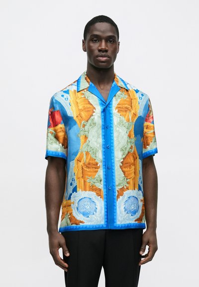 Πουκάμισο με κοντά μανίκια σε μπλε χρώμα με έντονο πολύχρωμο σχέδιο που απεικονίζει αρχιτεκτονικά στοιχεία και ζώα. Λεία υφή με κούμπωμα μπροστά με κουμπιά.