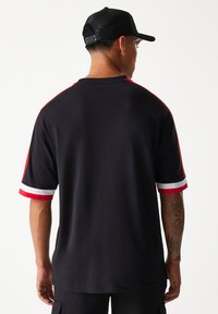 Fekete rövid ujjú ing, piros és fehér csíkos díszítéssel az ujjakon, pamut anyagból készült, laza szabású.