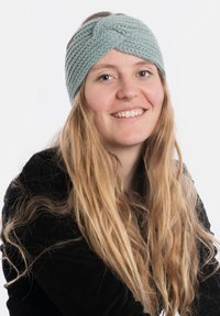 Fascia in maglia di colore azzurro chiaro con un design intrecciato; texture morbida; indossata da una persona con capelli lunghi e mossi e una maglietta nera.