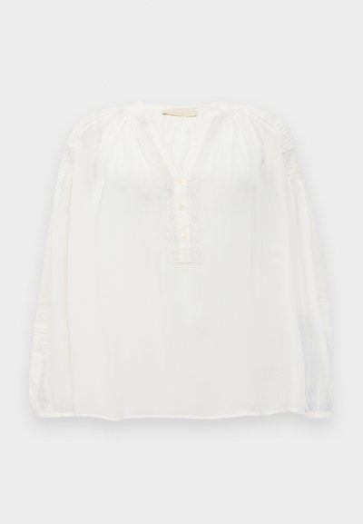 Blouse blanche à manches longues avec bord en dentelle, trois boutons sur le devant, épaules froncées et délicats détails de pintucks sur les manches.