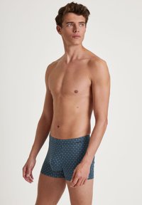 Boxershorts van donkerblauwe stof met een geometrisch ruitpatroon. Fitted ontwerp, gladde textuur, middenhoge taille en geen zichtbare naden.