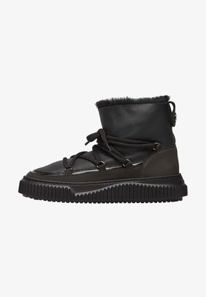 Bottes en cuir noir avec une semelle en caoutchouc texturé, doublure en fourrure sur le dessus et lacets fonctionnels. Présente une finition lisse et une construction robuste.