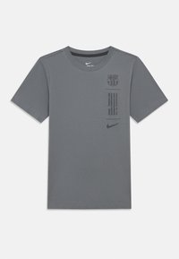 Sivý tričko Nike s krátkymi rukávmi, okrúhlym výstrihom, logom Barcelony a potišteným textom vpredu. Jednoduchý dizajn s hladkou textúrou.