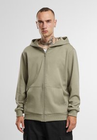 Olijf groene rits hoodie van zacht materiaal, met een kangoeroezak en ribgebreide manchetten, in een ontspannen pasvorm en met capuchon.