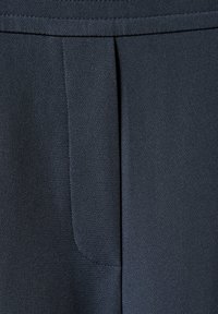 Donkerblauwe stof close-up met een gladde textuur, voorzien van een enkele plooi en fijn gestikte naden.