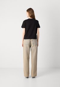 Zwarte cropped t-shirt met korte mouwen, gecombineerd met hooggetailleerde beige wijde jeans. Soepele stof en ontspannen pasvorm. Eenvoudig ontwerp.