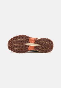 La semelle de la chaussure de trail running présente une semelle extérieure en caoutchouc brun robuste avec des crampons profonds, des accents orange et une surface texturée pour une meilleure adhérence.