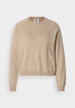 Beige sweater in soft, textured fabric with a crew neckline. Features long raglan sleeves and a ribbed hem. Label visible inside collar.