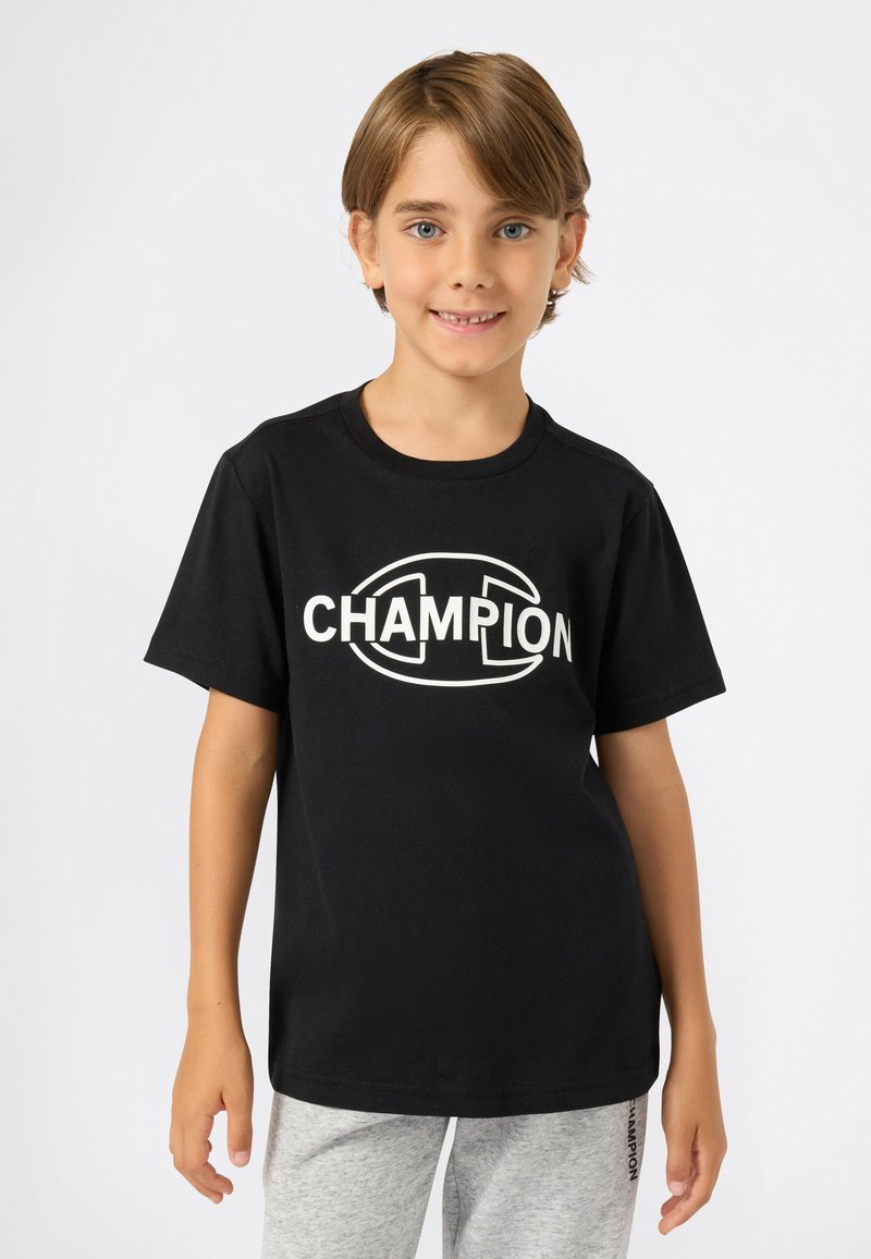 Svart bomulls T-skjorte med korte ermer, som har en iøynefallende hvit "CHAMPION" logo på brystet. Enkel rund halslinje og avslappet passform.