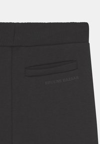 Calças de treino pretas com um cós canelado, pequeno bolso lateral e a marca discreta "BRUUNS BAZAAR" impressa na parte de trás. Material suave em mistura de algodão.