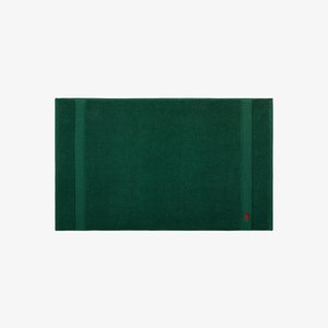 Tapis de bain en coton vert avec une surface texturée, présentant deux bandes horizontales et un petit logo dans un coin.