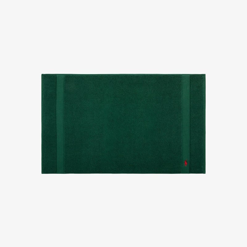 Tapis de bain en coton vert avec une surface texturée, présentant deux bandes horizontales et un petit logo dans un coin.
