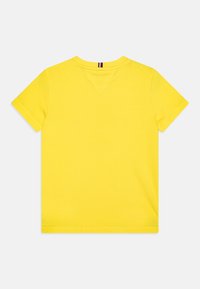 Camiseta de algodón amarilla con mangas cortas, cuello redondo y un diseño de yugo trasero triangular. Textura suave, sin patrones ni acentos.