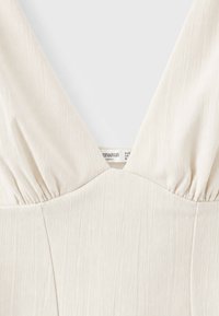 Robe sans manches ivoire avec un col en V profond et un tissu subtilement texturé de la marque Divarius, taille moyenne.