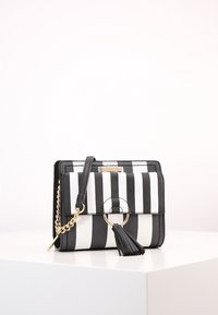 Borsa a strisce bianca e nera realizzata in materiale sintetico, con un pon-pon decorativo, accessori in metallo dorato e tracolla a catena.