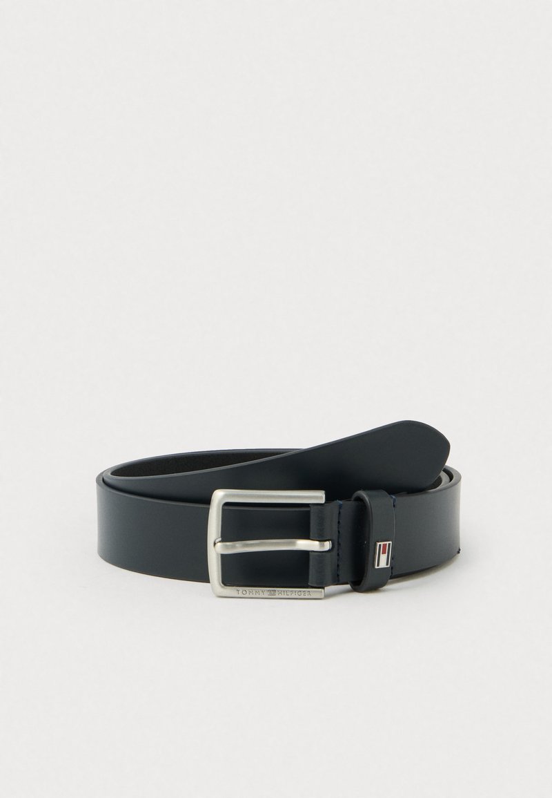 Tumesin nahkrihm hõbedase metallpannaga, millel on logo aktsent. Rihmal on sile tekstuur ja klassikaline disain.