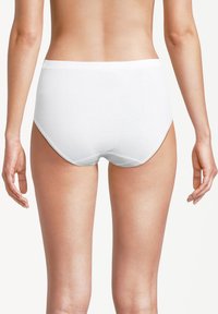 Eine Frau trägt schlichte wei�ße Baumwollslips, von hinten betrachtet, vor einem weißen Hintergrund.