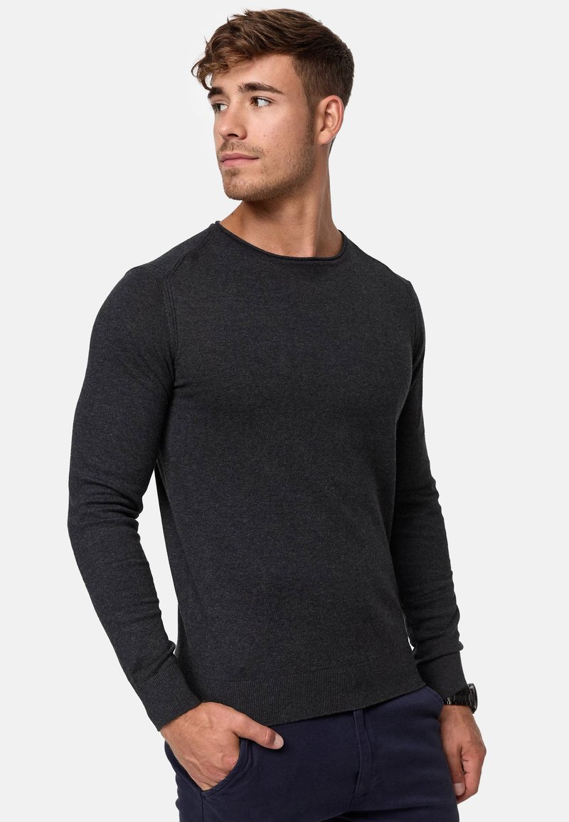 Pull long gris foncé à manches longues avec un col rond et des poignets et un ourlet côtelés. Fait en tissu tricoté texturé, coupe ajustée.