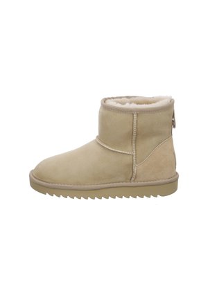 Botte d'hiver beige montant à la cheville avec une doublure douce en peau de mouton, une semelle texturée et des coutures renforcées sur fond blanc.