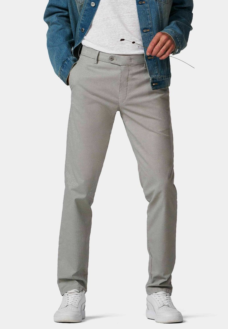 Pantalon gris en tissu texturé avec une coupe droite. Doté de poches avant, de passants de ceinture et d'une fermeture bouton. Porté avec des baskets blanches.