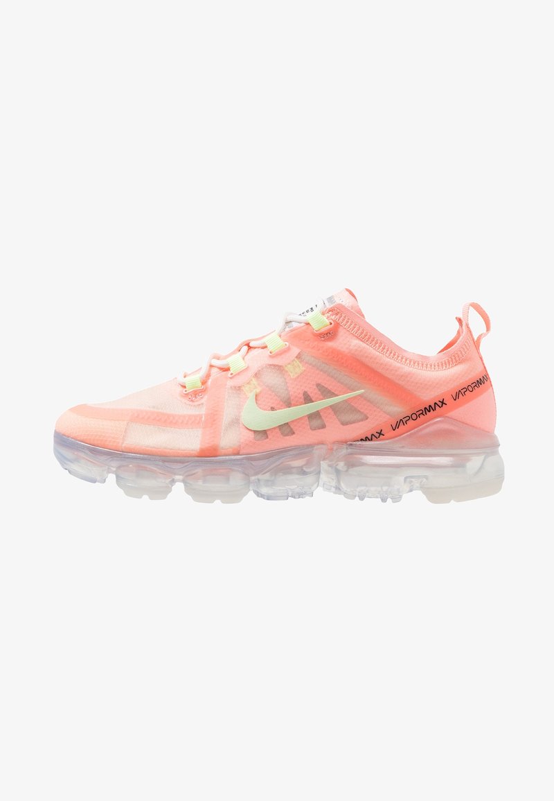Baskets Nike Vapormax rose corail avec semelle à coussin d'air transparente, logo Swoosh vert clair, lacets blancs et texte noir "Vapormax" sur la bande du talon.