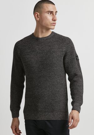 Pullover grigio scuro a maglia con scollatura a girocollo, tessuto testurizzato, polsini a coste e un'etichetta del marchio sulla manica sinistra.