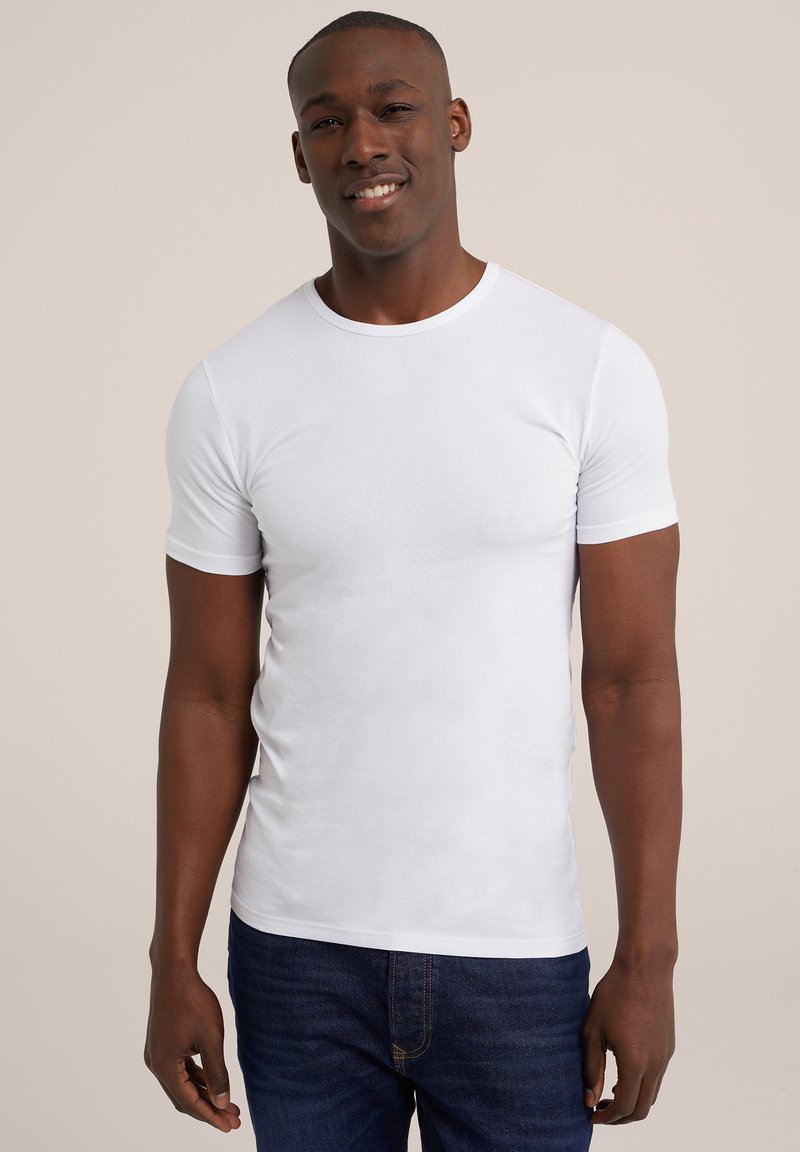 Witte katoenen t-shirt met korte mouwen, ronde halslijn en een slim fit. Draagt met blauwe denim jeans, weergegeven tegen een neutrale achtergrond.