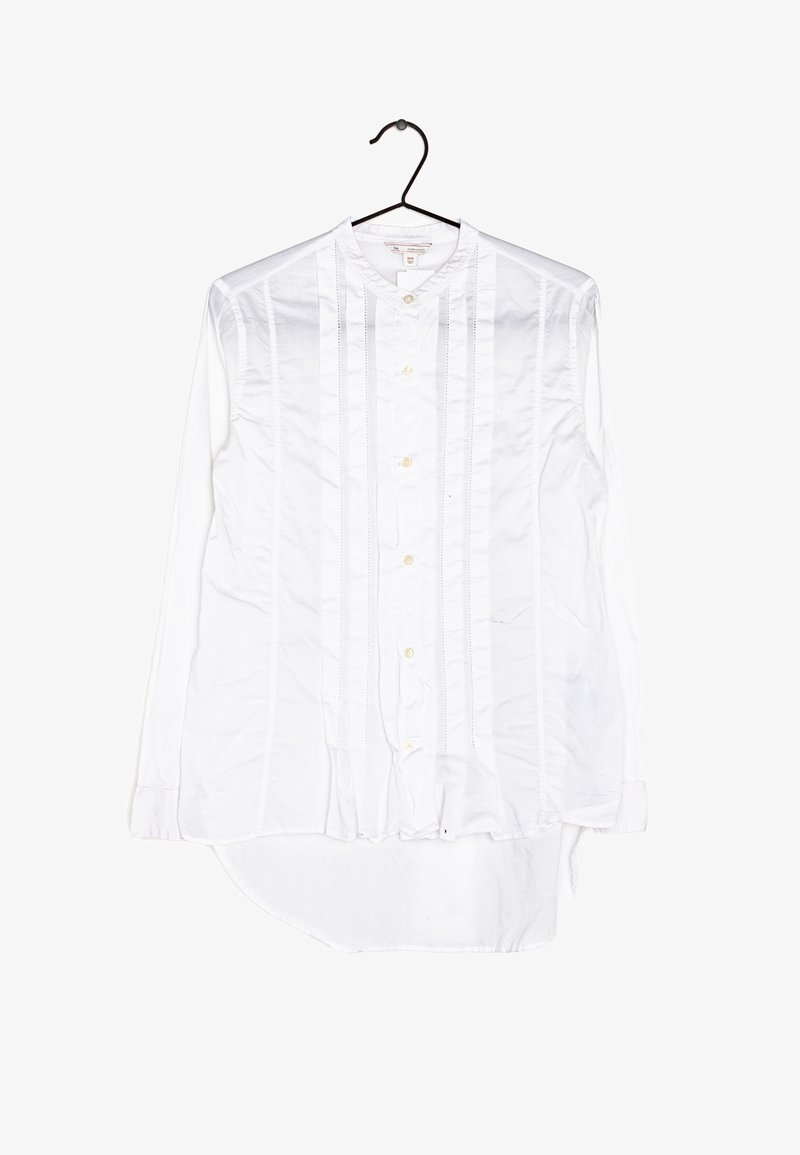 Chemise blanche à manches longues avec col montant, présentant des détails de coutures verticales et des boutons sur le devant. Tissu en coton lisse.