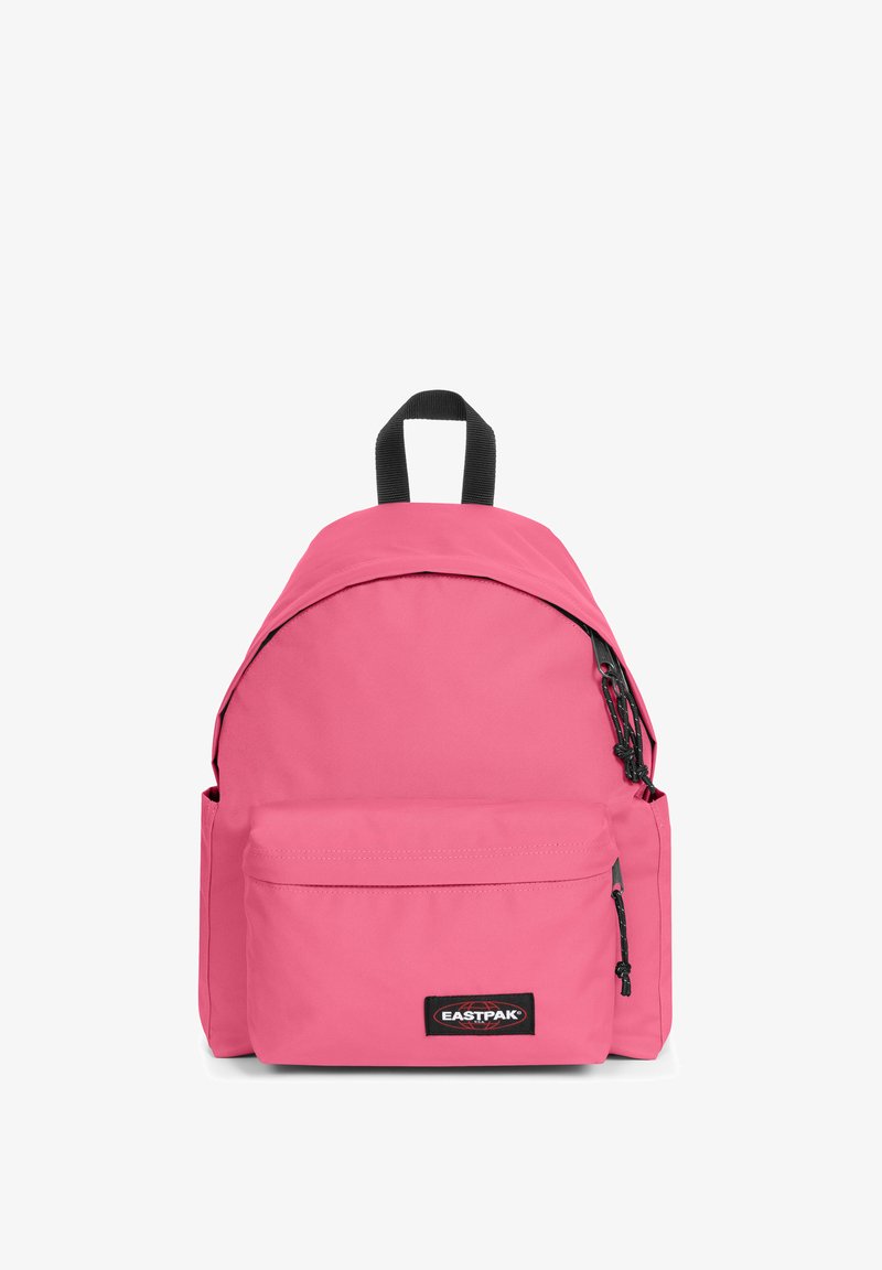 Różowy plecak wykonany z wytrzymałego materiału. Posiada zaokrąglony kształt, zapinaną na zamek przednią kieszeń oraz czarne akcenty, w tym regulowane szelki.
