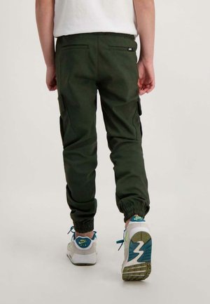 Groene cargobroek met elastische boorden, voorzien van zij- en achterzakken, gemaakt van stevig materiaal. Draag met witte en teal sneakers.