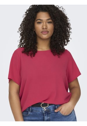 Top fucsia a maniche corte realizzato in tessuto leggero, con una forma rilassata e una texture liscia, abbinato a jeans in denim blu e una cintura nera.