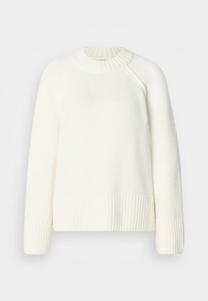 Krém színű pulóver bordázott nyakkivágással és mandzsettákkal. Puha, texturált anyagból készült. Laza szabással és raglán ujjakkal rendelkezik.