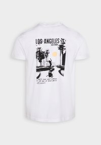 Camiseta blanca de algodón con un gráfico en negro y amarillo que incluye palmeras, un skater y texto promocionando Venice Beach, California.
