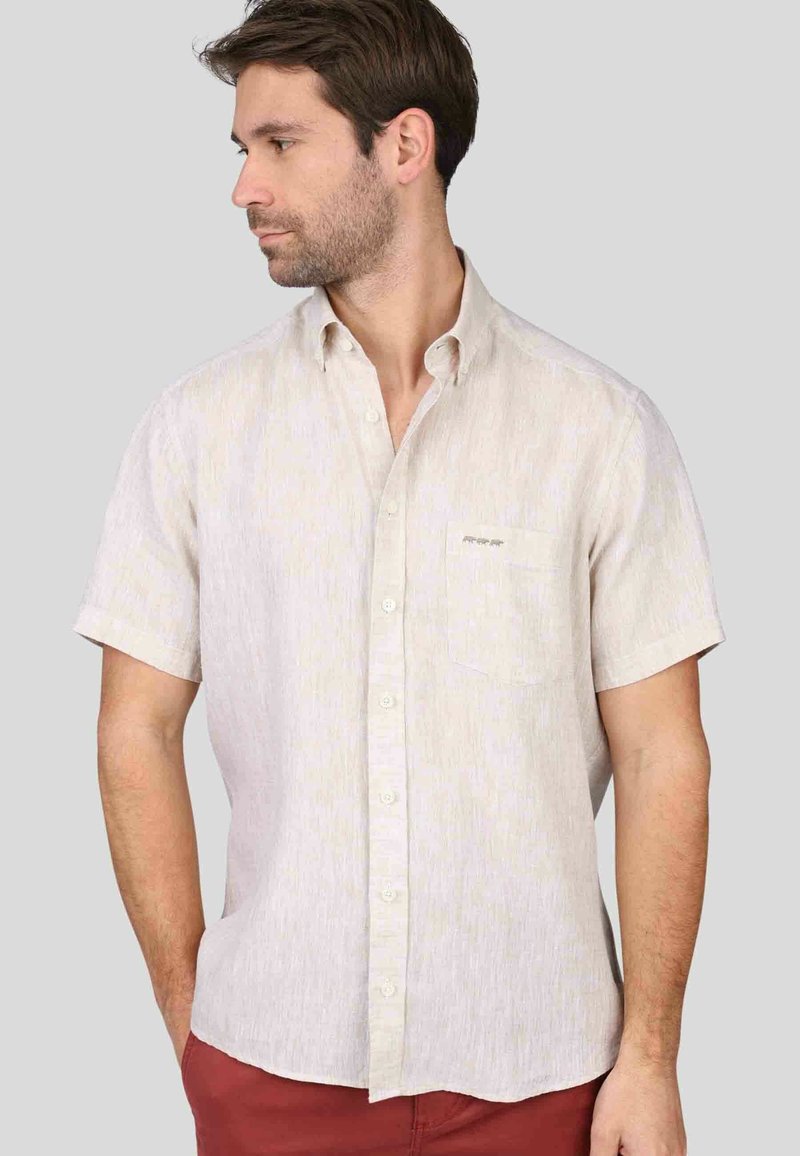 Chemise beige à manches courtes avec un motif texturé subtil, col boutonné, poche poitrine et boutons blancs.