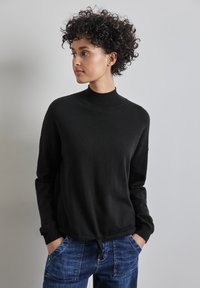 Schwarzer gestrickter Pullover mit hohem Kragen, langen Ärmeln und Kordelzugsaum. Der Stoff wirkt weich und hat eine leicht lockere Passform.