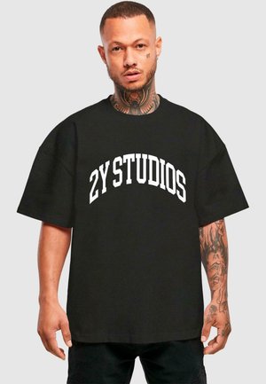 Black oversized T-shirt made of cotton, featuring a white curved text "2Y STUDIOS" on the chest. Short sleeves and relaxed fit design.