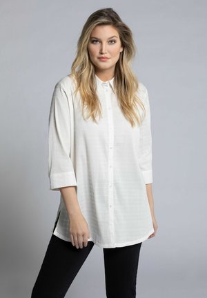 Witte gestreepte overhemd met een kraag en driekwartmouwen, voorzien van zijsplitten. Gekozen in combinatie met donkere skinny jeans.
