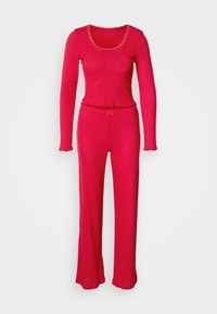 Ensemble lounge en maille côtelée rouge comprenant un haut à manches longues avec un décolleté festonné et un pantalon assorti à taille ajustée et jambes évasées.