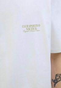 Baltas kokvilnas T-krekls ar mazu zelta logo tekstu "CLUB SPORTIVO NAUTICO" un "Originals Summer Edition" kreisajā krūtīs.
