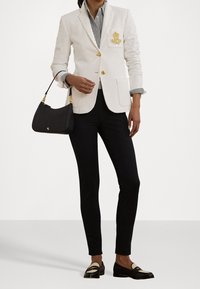 Bílý blazer se zlatými knoflíky a logem, pruhovaná košile, černé slim kalhoty, černá kabelka se zlatými detailem a černé mokasíny.